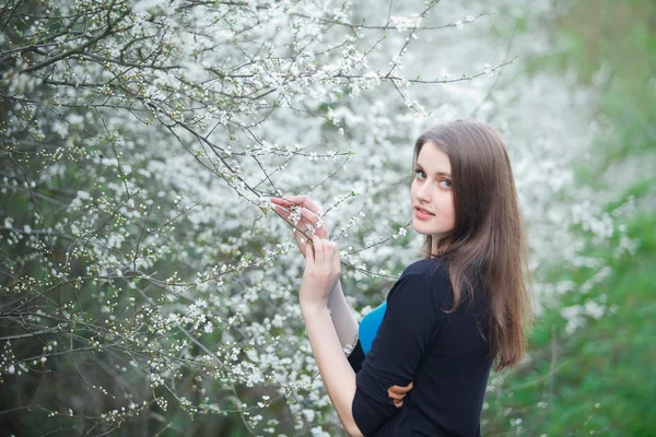 Portrait of a brunette woman inhales the scent of flowers — Stock Photo, Image