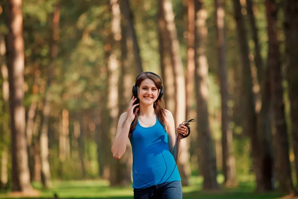 Girl walks in the park with headphones — Stockfoto