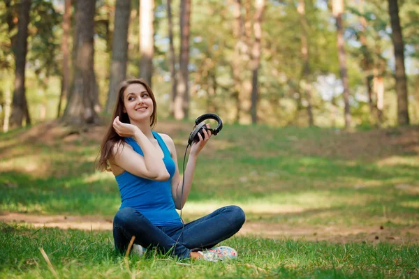 Girl and headphones in park — Stockfoto