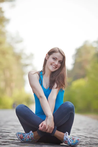 Smiling girl sitting on the road — Stock Photo, Image