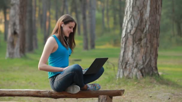 Jovem mulher bonita falando e trabalhando usando laptop na natureza — Vídeo de Stock