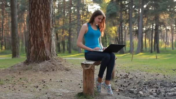 Молода красива жінка використовує ноутбук в літній день — стокове відео
