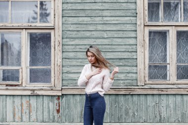 Örme kazak penceresi olan eski ahşap ev arka plan üzerinde güzel kadın