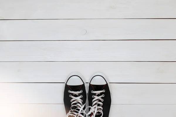 Zwarte sneakers met veters op een witte houten vloer. bovenaanzicht — Stockfoto