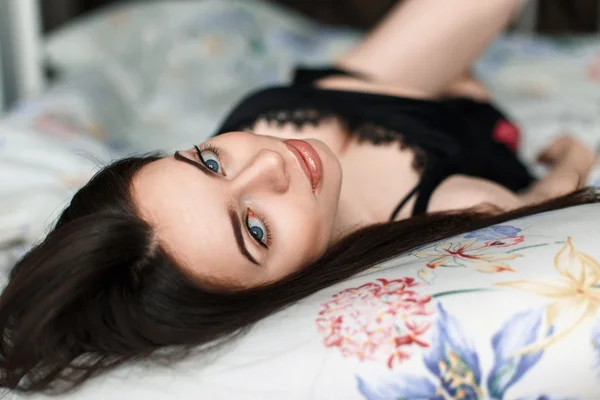 Hermosa morena acostada en la cama y mirando a la cámara . — Foto de Stock