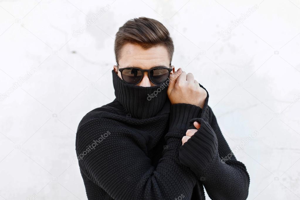 Young fashionable guy in black sunglasses vite and covers the face with a cloth.