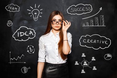 Iş simgeleri ve diyagramları arka planda beyaz bir bluz gözlük ile genç güzel kız. Başarılı bir iş kadını kavramı