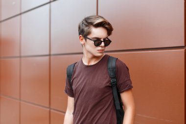 Güneş gözlüğü ve bir duvara yakın duran çanta şık yakışıklı adam.