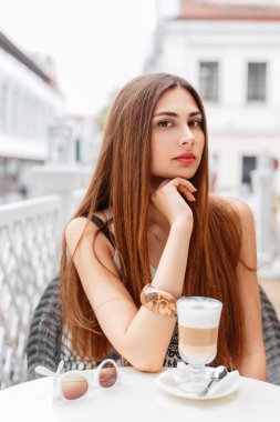 Güzel genç kız bir yaz kafede lezzetli kahve içiyor. İyi bir tatil kavramı.