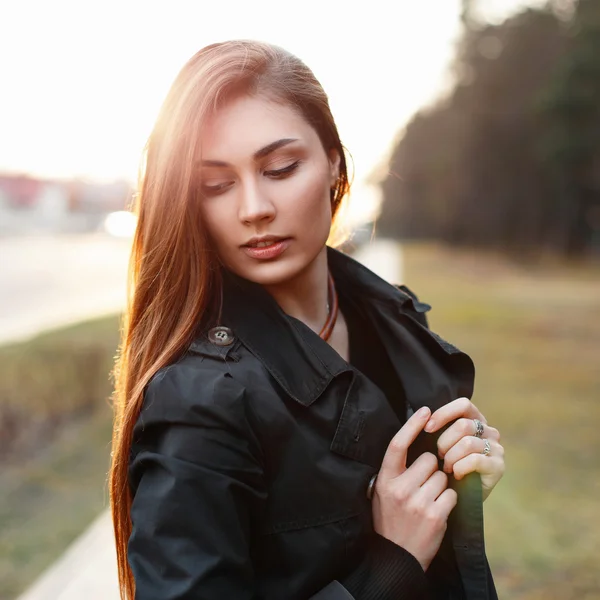 Stylowa dziewczyna w czarnym płaszczu, pozowanie na słoneczny dzień. — Zdjęcie stockowe