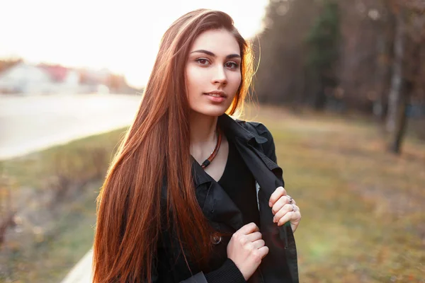 Piękna stylowa dziewczyna w czarnym płaszczu, spaceru w parku w dzień wiosny o zachodzie słońca. — Zdjęcie stockowe