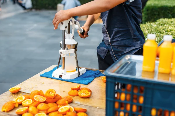Man squeezes orange juice. Outdoors. — Stock Photo, Image