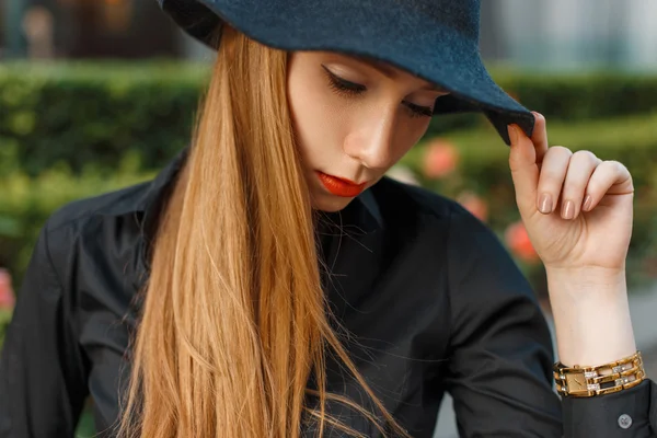 Stijlvolle jong meisje in een zwarte hoed, shirt, horloges. — Stockfoto