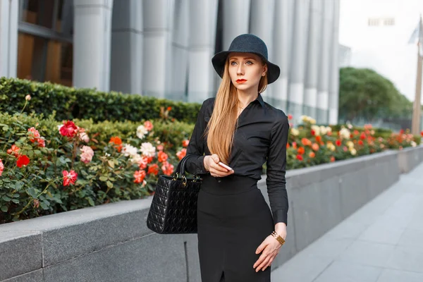 Mulher de negócios moderna em uma roupa elegante andando perto do edifício com flores . — Fotografia de Stock