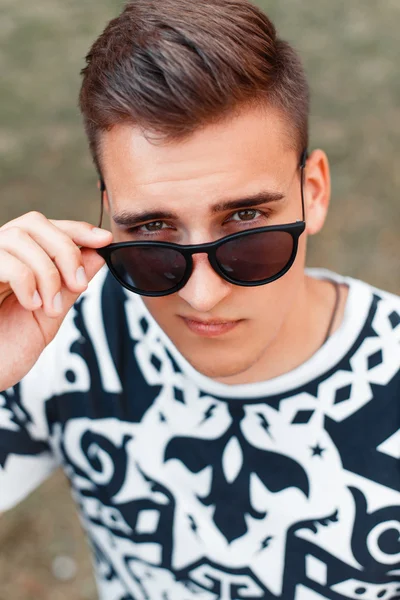 Jeune bel homme aux lunettes de soleil levant les yeux — Photo