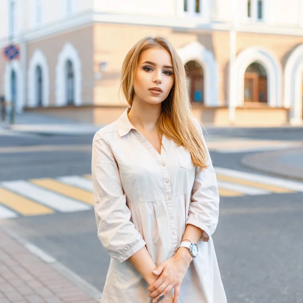 Menina bonita elegante em roupas da moda em pé no fundo da estrada e casas . — Fotografia de Stock