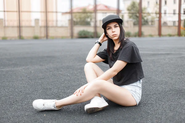 Hermosa chica con ropa negra con estilo y una gorra de béisbol descansando en un día de verano — Foto de Stock