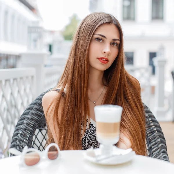 Piękna młoda dziewczyna z czerwonymi ustami opiera się w kawiarni na słoneczny dzień. — Zdjęcie stockowe