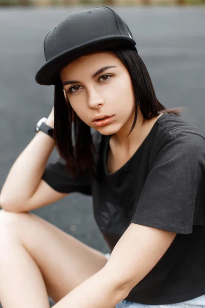 Young beautiful girl in stylish black cap on a dark background. — Stock Photo, Image