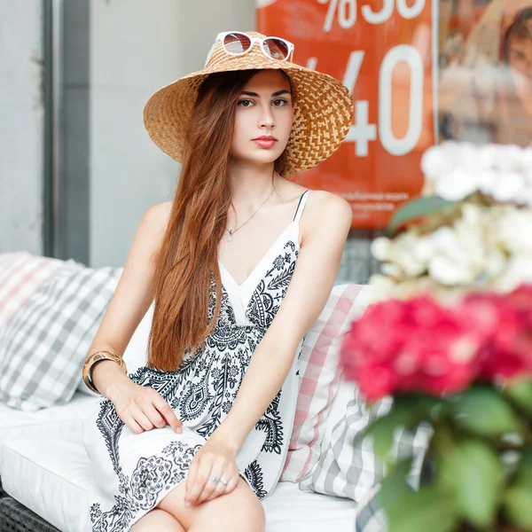 Elegante mujer hermosa en un sombrero y gafas de sol descansando en el sofá después de ir de compras . — Foto de Stock