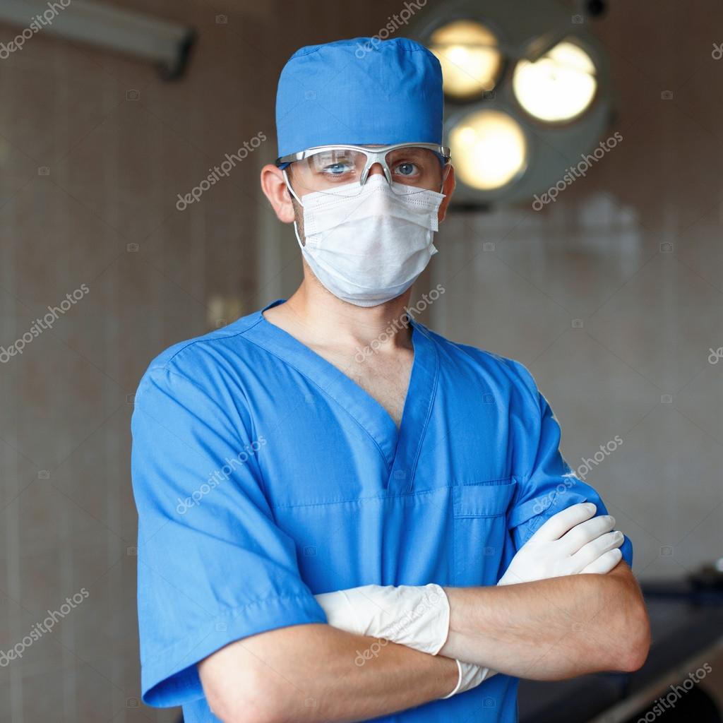 Surgeon In Blue Uniform Glasses And Hat Stands In The