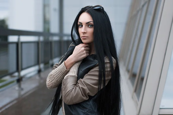 Girl in a leather jacket standing near the building — Stock Photo, Image