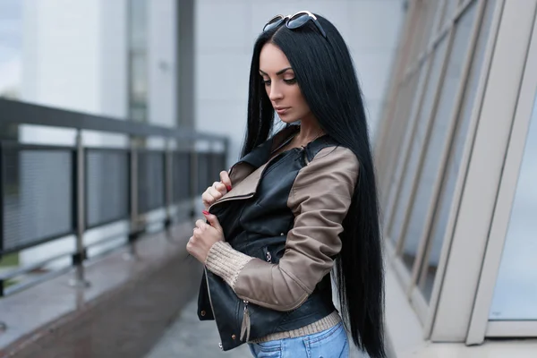 Chica en una chaqueta de cuero de pie cerca del edificio —  Fotos de Stock