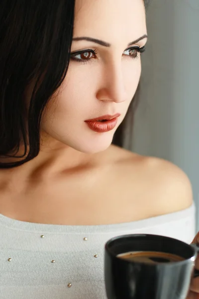Schönes Mädchen, das am Fenster mit Kaffee steht — Stockfoto