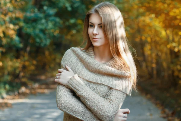 Красивая девушка в свитере, стоящая в осеннем парке — стоковое фото