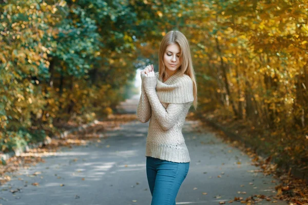 Nette Frau im Trikot steht im Herbstpark — Stockfoto