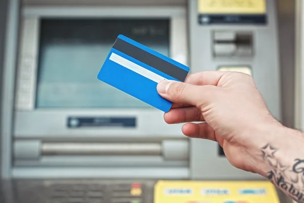 Mão segurando cartão de plástico perto de ATM. Pagamento por cartão bancário . — Fotografia de Stock