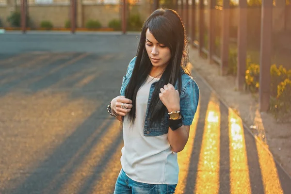 Hermosa chica en una chaqueta de mezclilla en la puesta de sol . — Foto de Stock