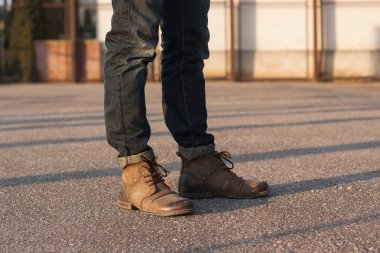 Kot pantolon ve bot ile erkekler bacaklar. Gün batımında hipster.