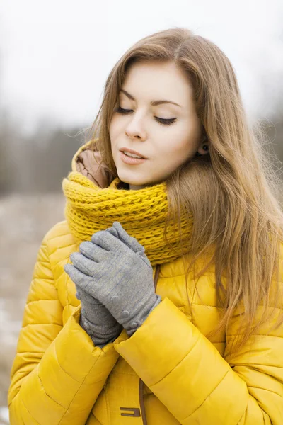 Pretty woman in a yellow knit scarf. Warm hands. Looking down. — Stock Photo, Image