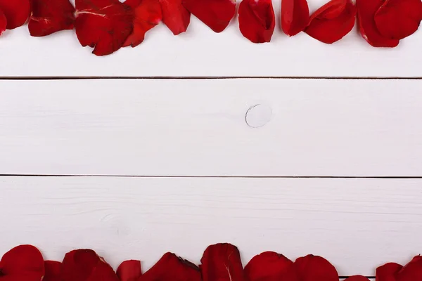 Pétalos de rosa sobre mesa de madera blanca . — Foto de Stock