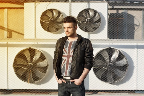 Beautiful guy in a black leather jacket. Stands near blades. — Stock Photo, Image