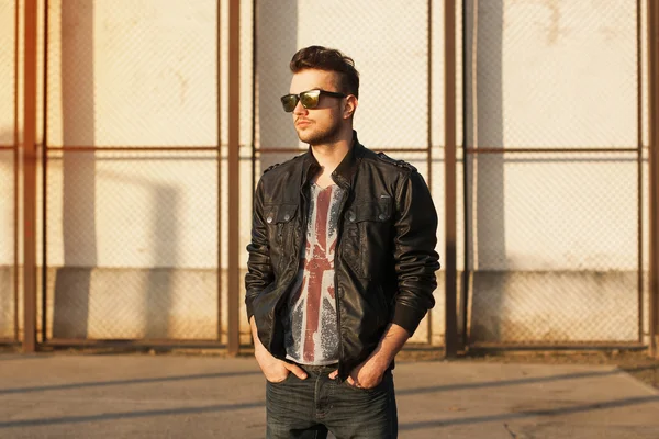 Portrait of a young man in a black leather jacket and sunglasses — Stock Photo, Image