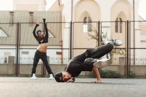 Young handsome dancer dancing hip-hop. Pretty woman dancing on the background. — Stock Photo, Image