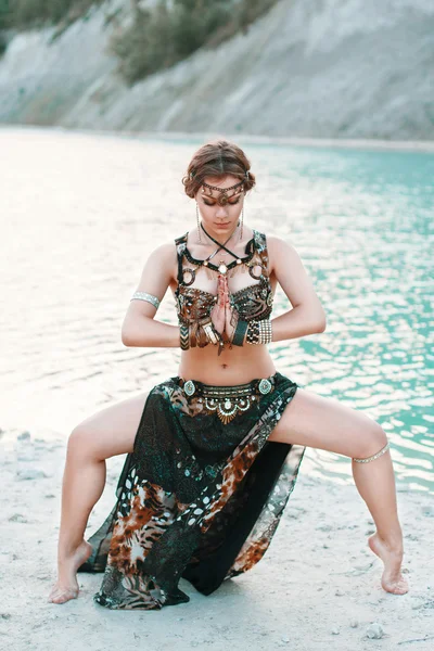 Hermosa chica en traje de fusión tribal de pie en una pose a orillas de la playa, fondo de mar azul . —  Fotos de Stock