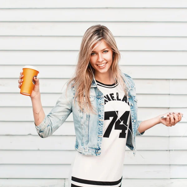 Pretty happy hipster girl enjoys music and drinks coffee. — Stock Photo, Image