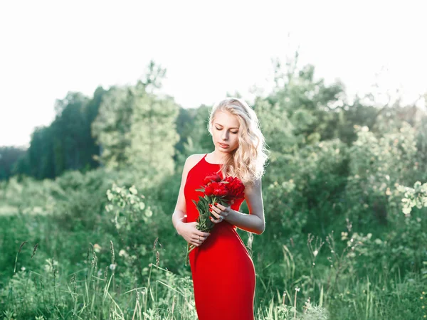 Ung vacker glad kvinna med blommor på ett fält, sommar — Stockfoto