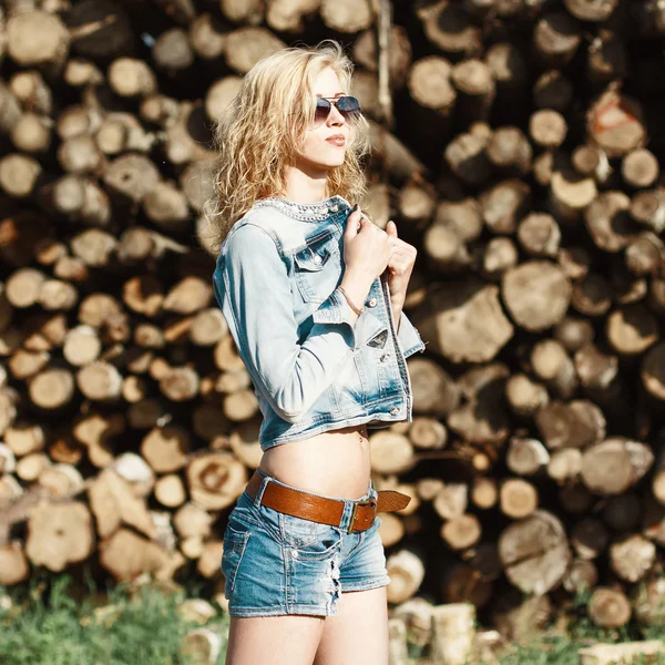 Portrait of a beautiful woman in sunglasses in denim shorts — Stock Photo, Image