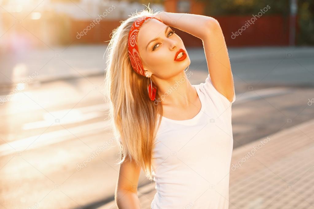 Pretty hipster girl with red lips resting on a background of rays the sunset. Vintage style clothing.