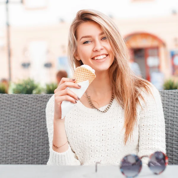 Chica sonriente comiendo una cucharada de helado en un cono de gofre — Foto de Stock