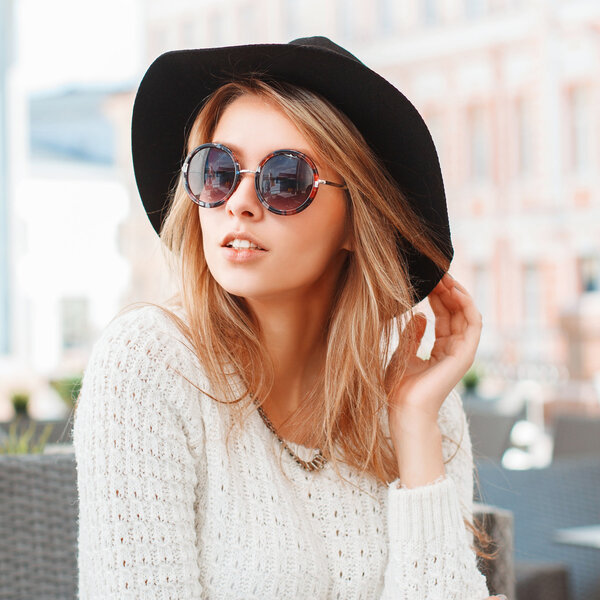 Pretty Fashionable woman with black hat and round sunglasses in cafe.
