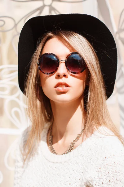 Portrait of a beautiful young girl in a black hat and round sunglasses on a sunny day. — Stock Photo, Image