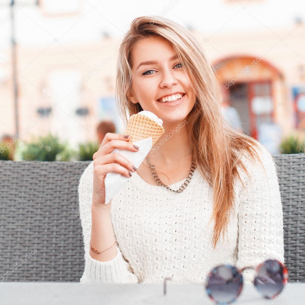 Smiling girl eating an ice-cream scoop in a waffle cone