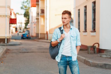 Young handsome man with a backpack in a denim shirt and jeans clothes traveling.