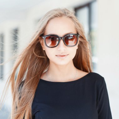 Pretty woman in sunglasses on background of windows.On a sunny day