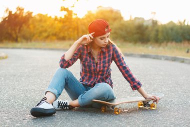 Woman with skateboard at sunset.